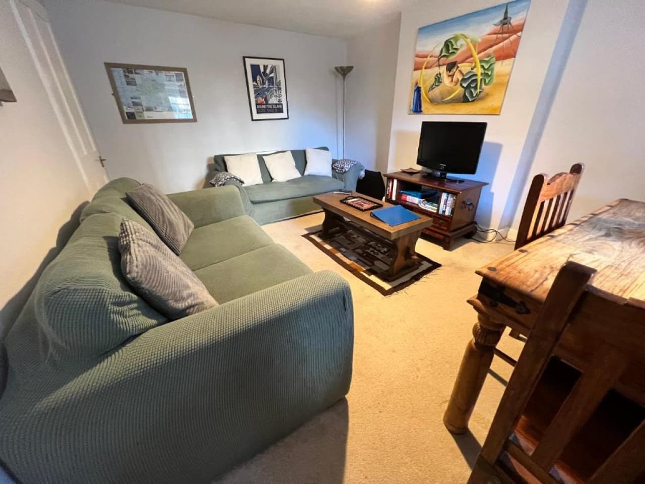 Living room - green sectional sofa, coffee table, flat-screen TV, dining chairs