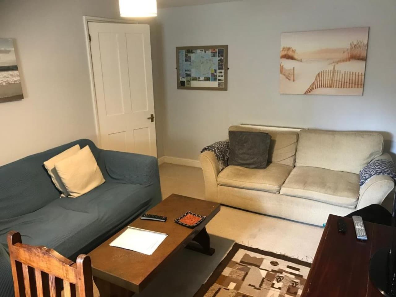Living room - two sofas, coffee table, patterned rug, framed map and seaside print
