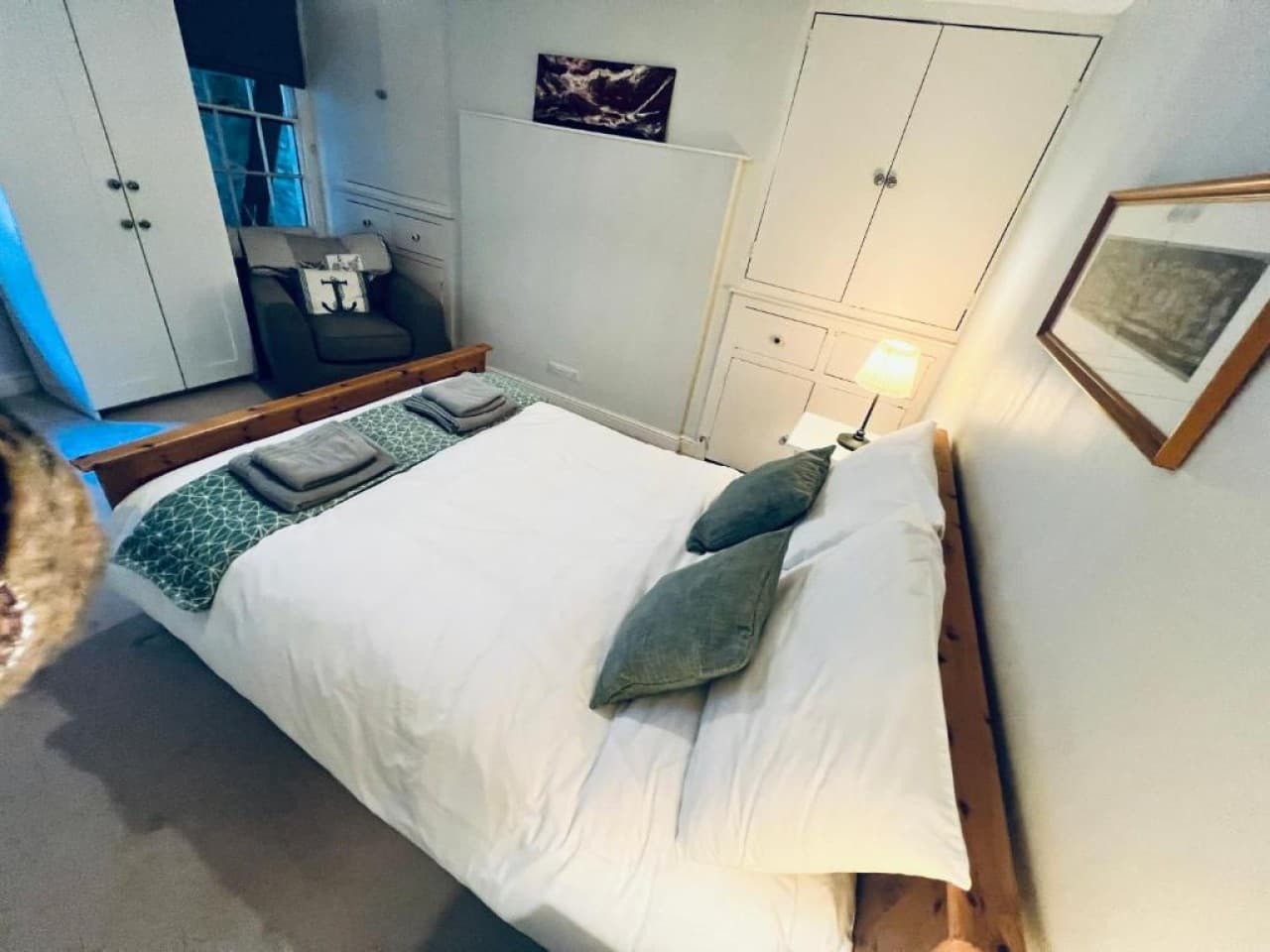 Bedroom 1 - double bed, white linens, green throw, built-in wardrobe (angle 3)