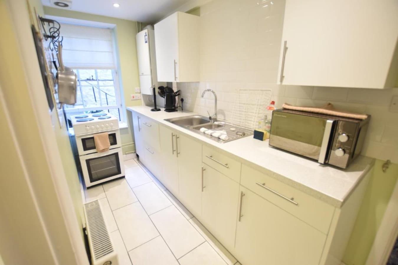 Kitchen - cream cabinets, electric hob and oven, microwave, coffee machine