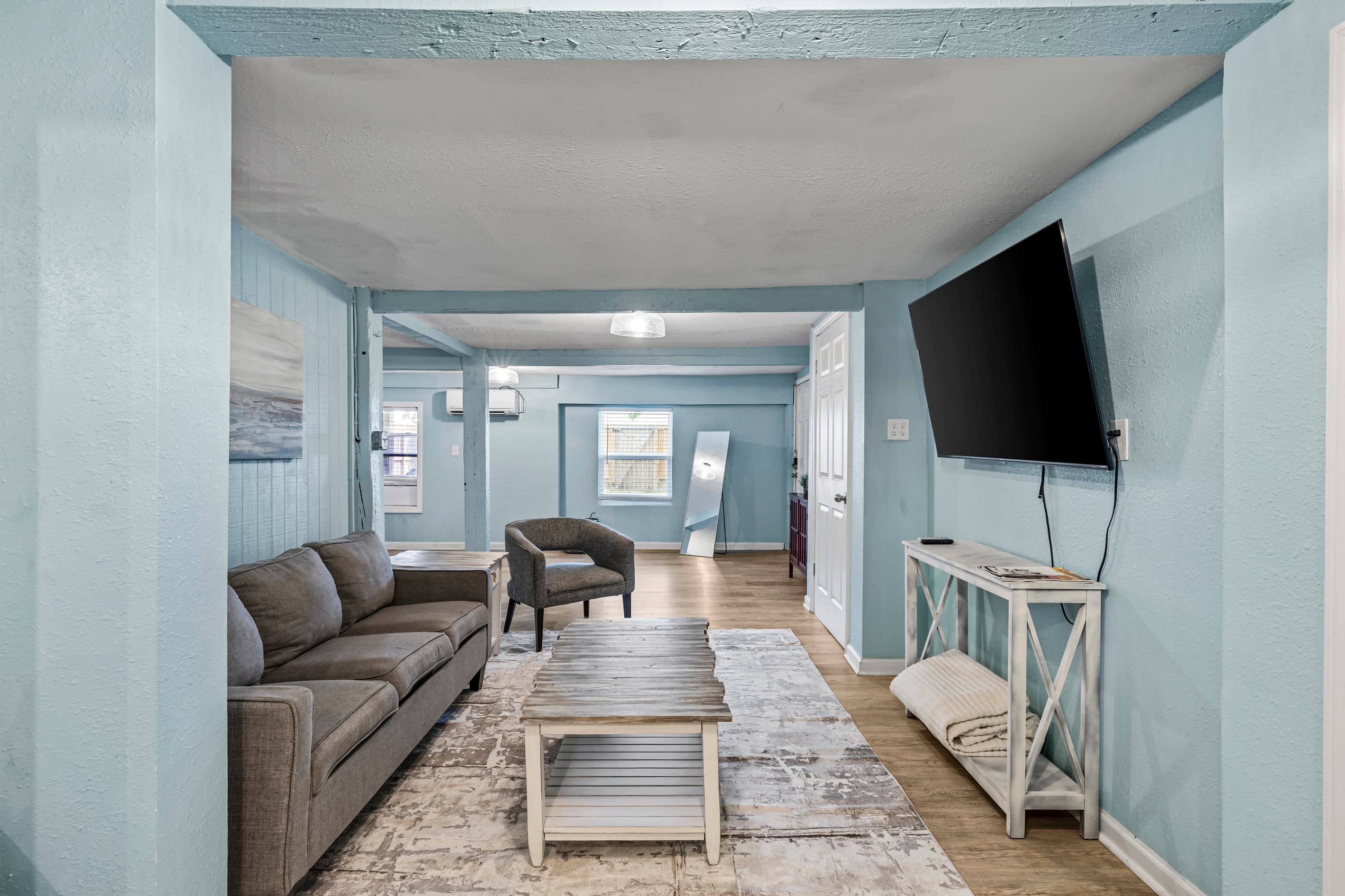 The full studio at a glance — living area in the foreground, sleeping space beyond, with original hardwood floors and teal character walls throughout.