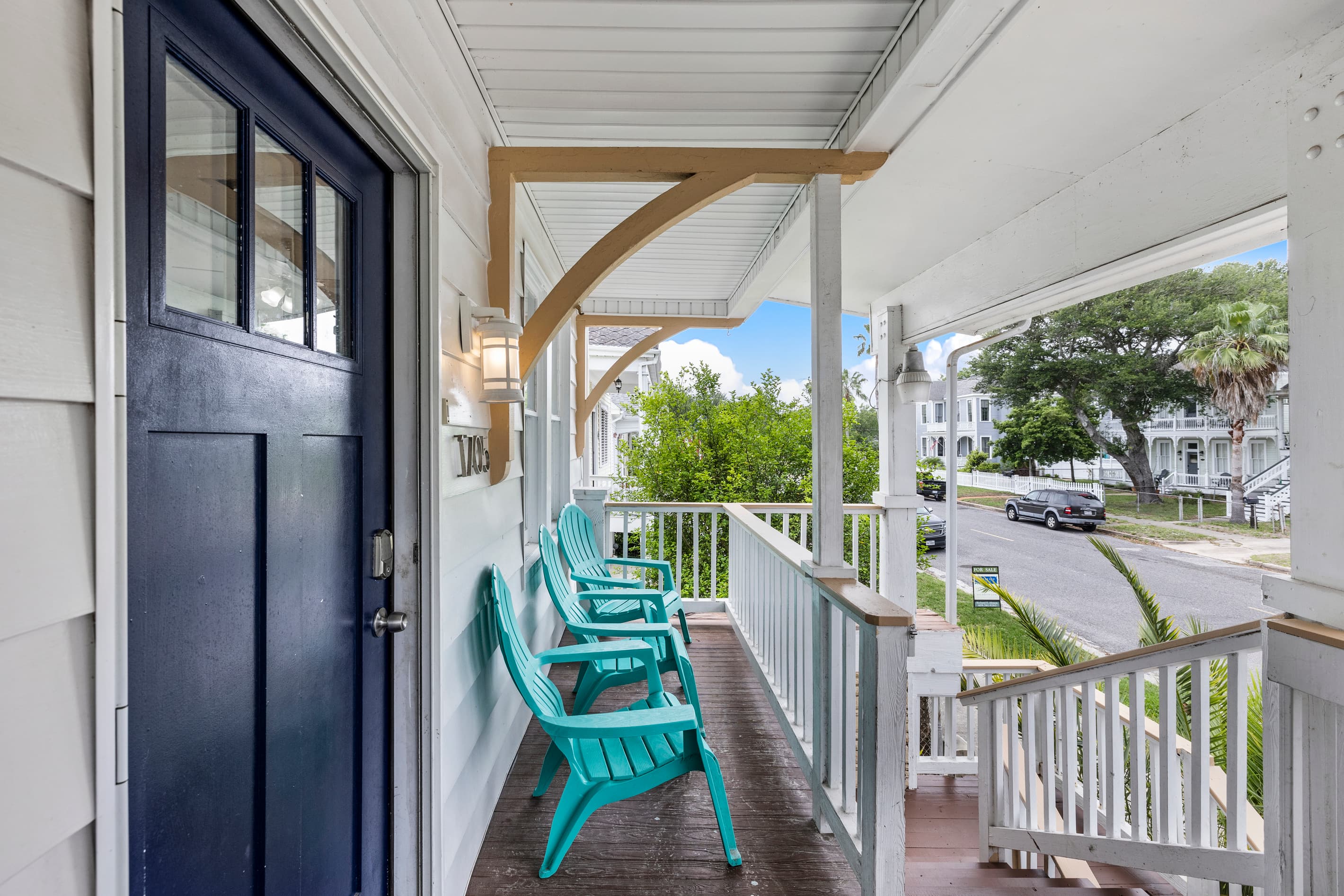 The covered front porch at Starboard at M — teal Adirondack chairs, classic Galveston architecture, and a front-row seat to the East End neighborhood.