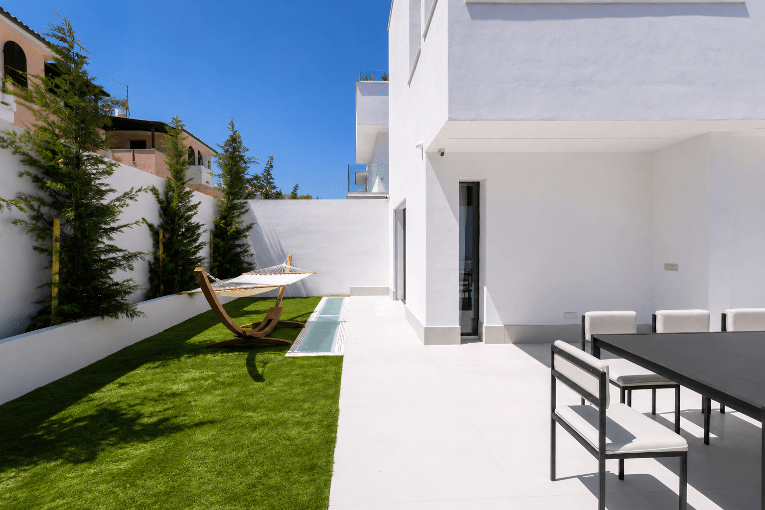 Private patio at AZULIS Villas Aramis in Golfo Aranci, with outdoor dining, green lawn, hammock corn