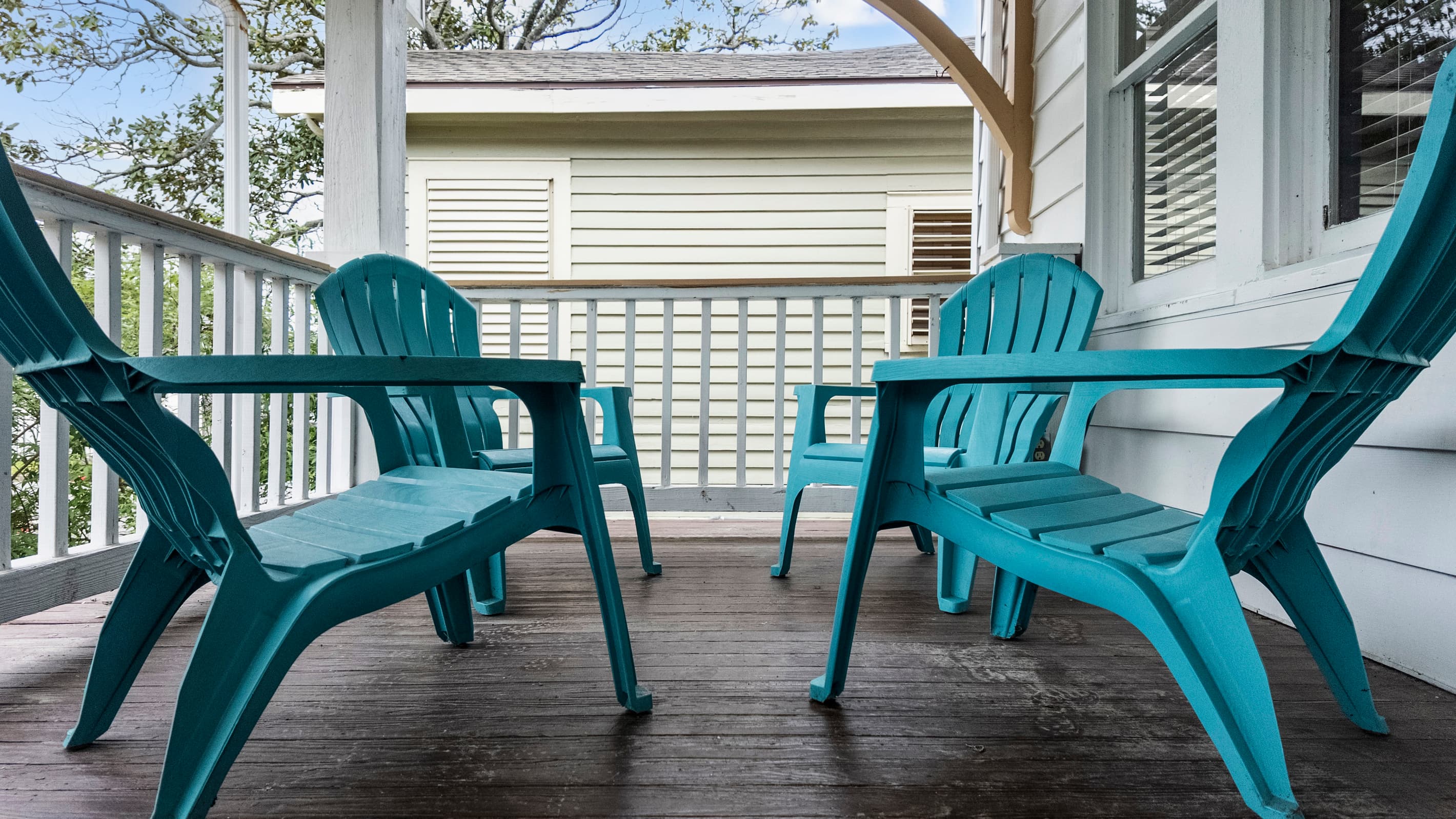 Relax on the screened porch with teal Adirondack chairs — a breezy spot for morning coffee or an evening wind-down.
