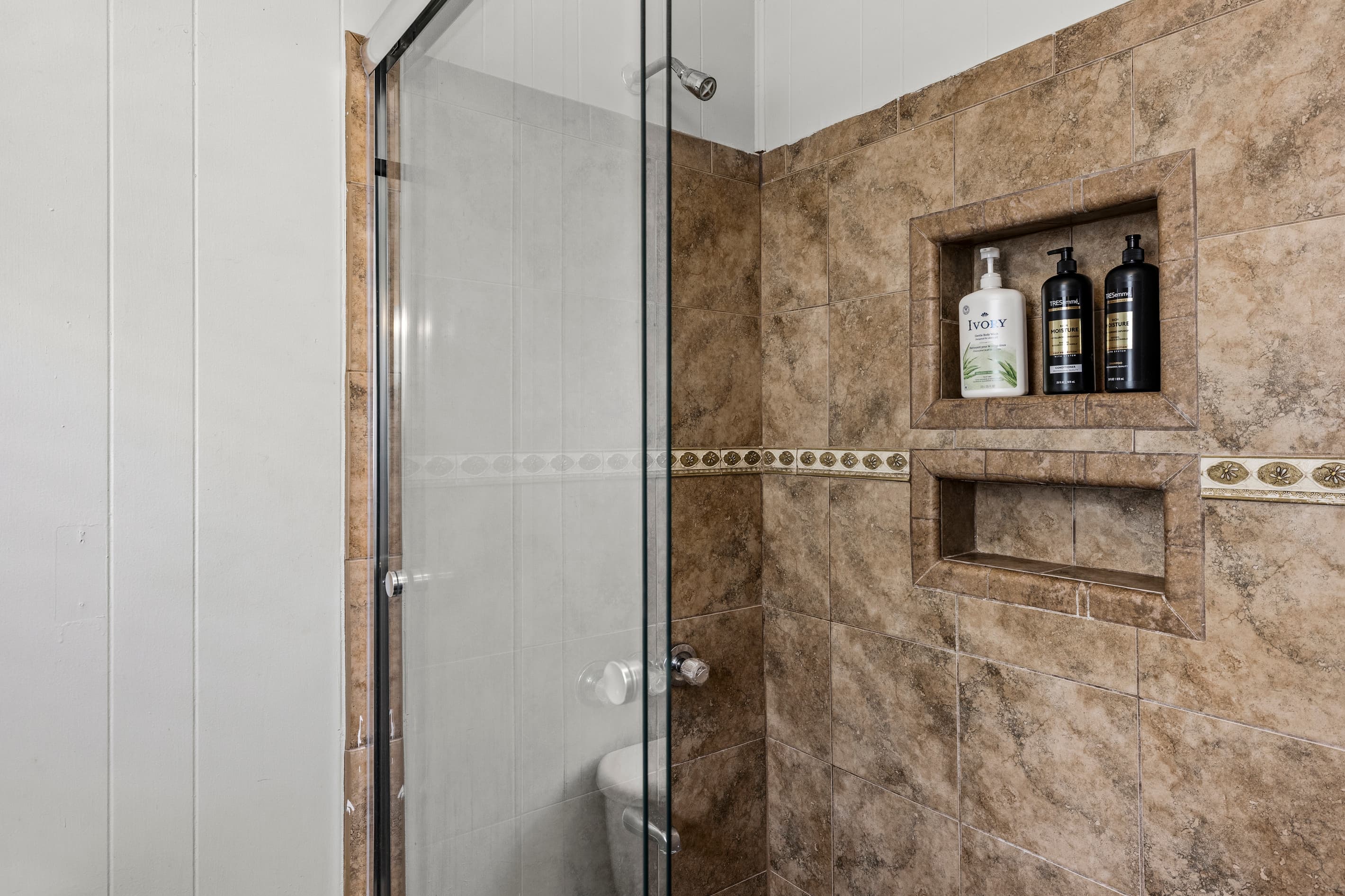 A renovated stand-up shower with crisp tile work — the perfect place to wash off the Galveston sun in the full bath.