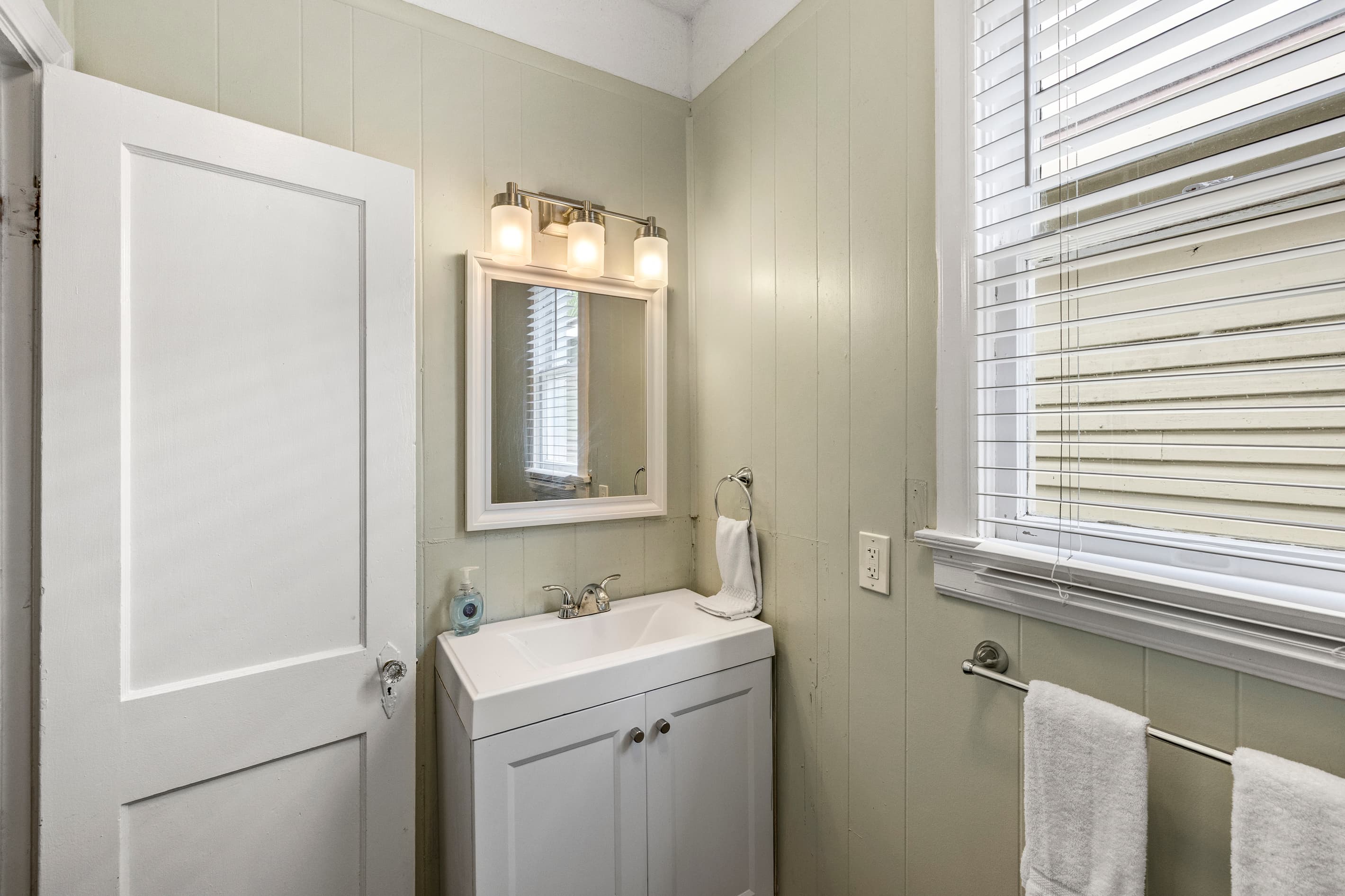 The full bathroom at Port Side at M features a bright vanity with ample mirror space — fresh towels and essentials provided.