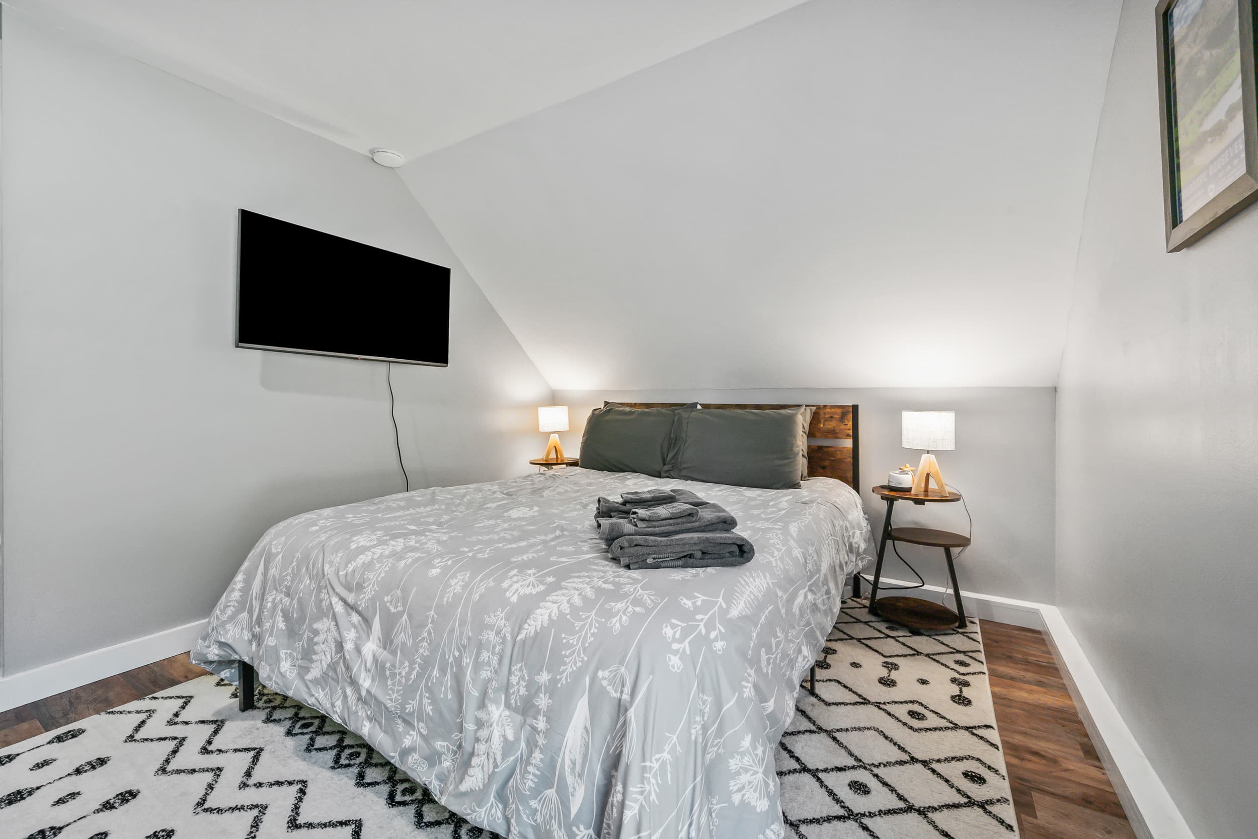 A comfortable bed with a smart tv next to it.