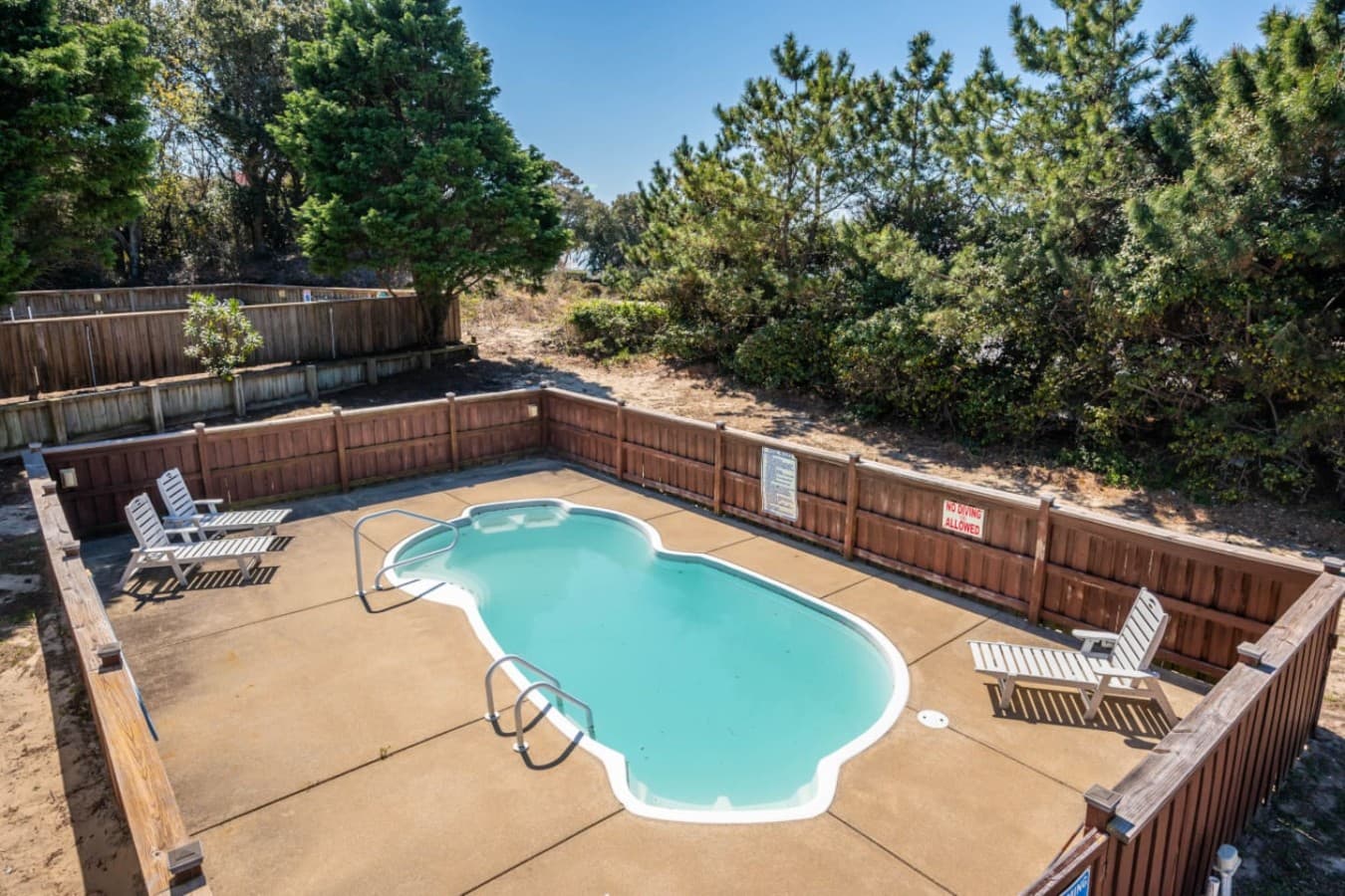 Elevated look at the private pool set within a fenced backyard.