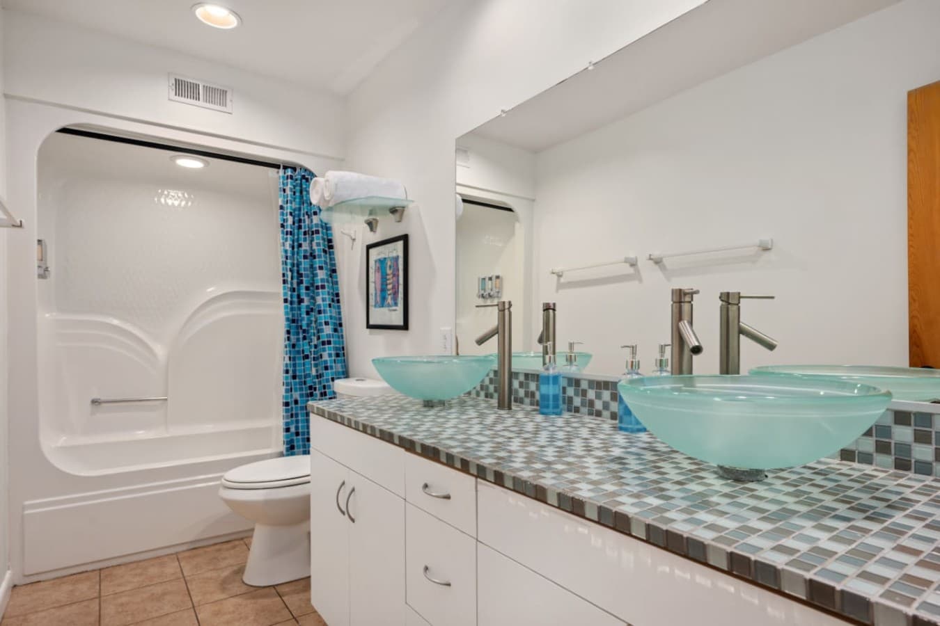 Bright bathroom w/ granite vanity, large mirror & clean, coastal finishes.