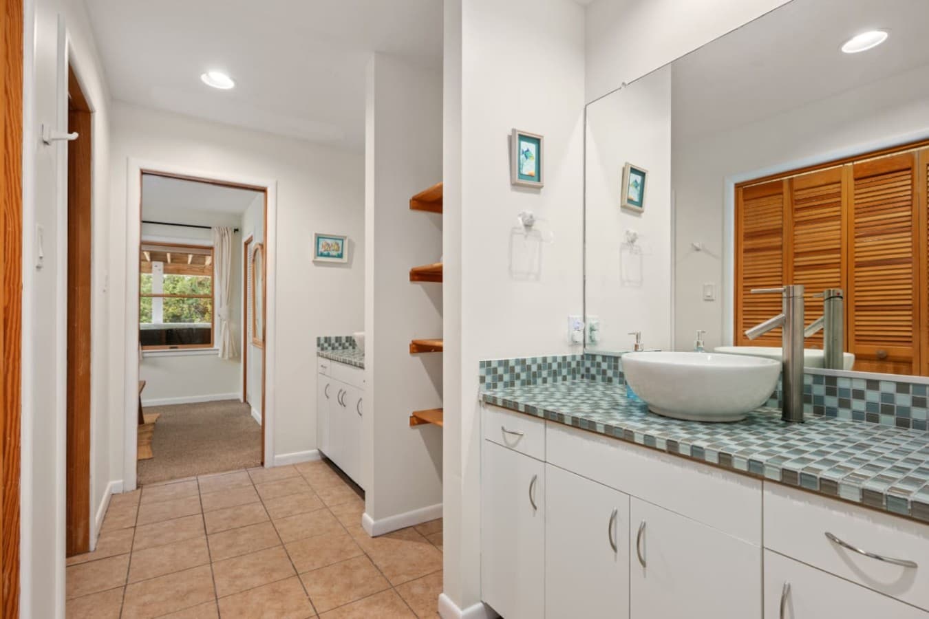 Vanity area w/ vessel sink, mosaic tile counter & built-in shelving just off the hallway.