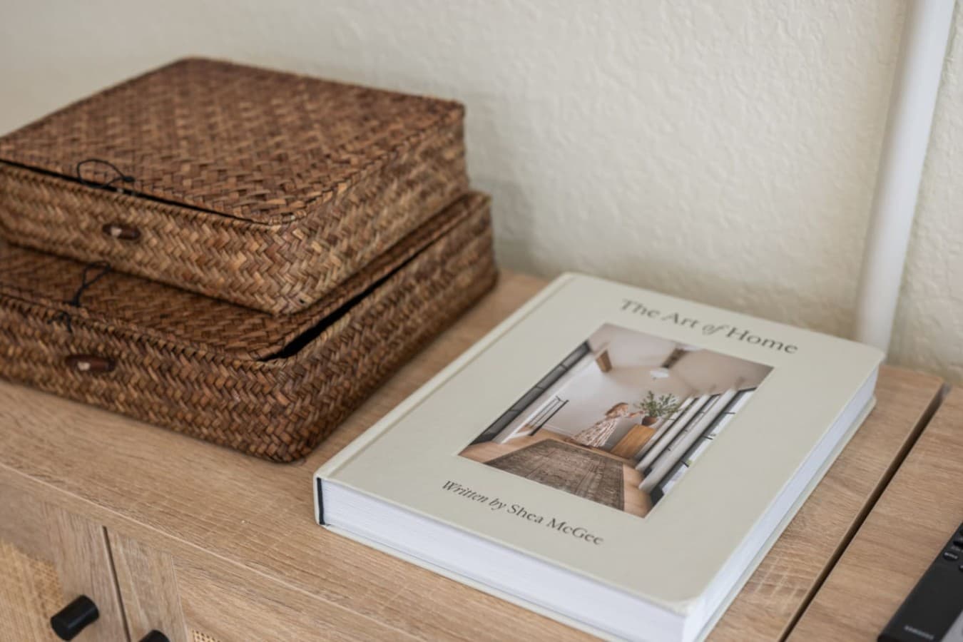 Detail shot of stacked woven storage baskets & a design book on the dresser top.