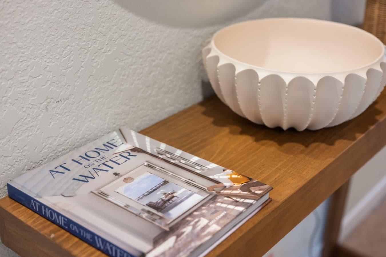 Console detail w/ a scalloped ceramic bowl & coastal design books stacked below.