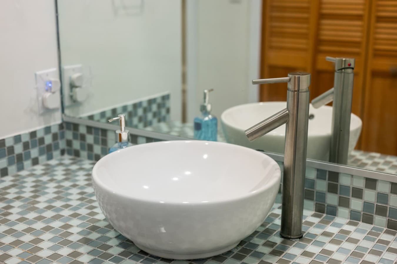 Bath detail w/ vessel sink, tall brushed faucet & sea-glass mosaic tile counter.