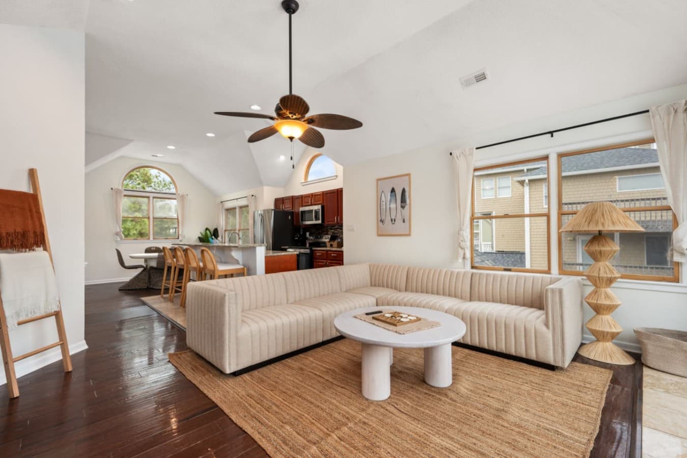 Open living room w/ curved sectional, jute rug & clear sightlines through to the kitchen.