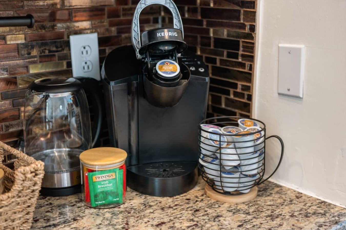Coffee station w/ single-serve brewer, electric kettle, tea tin & a pod carousel.