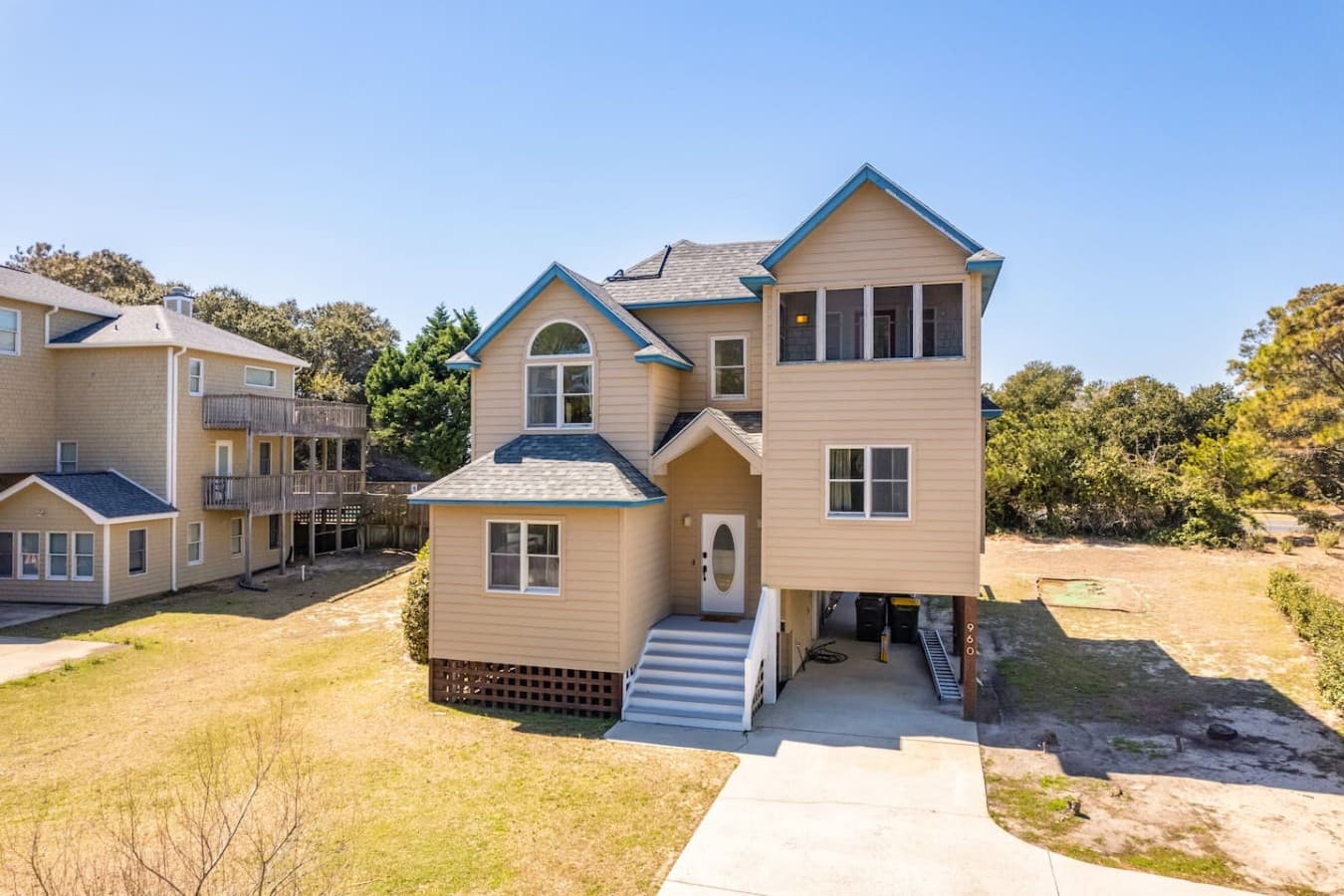 Elevated coastal home w/ shingled gables, wide entry stairs & parking tucked underneath.