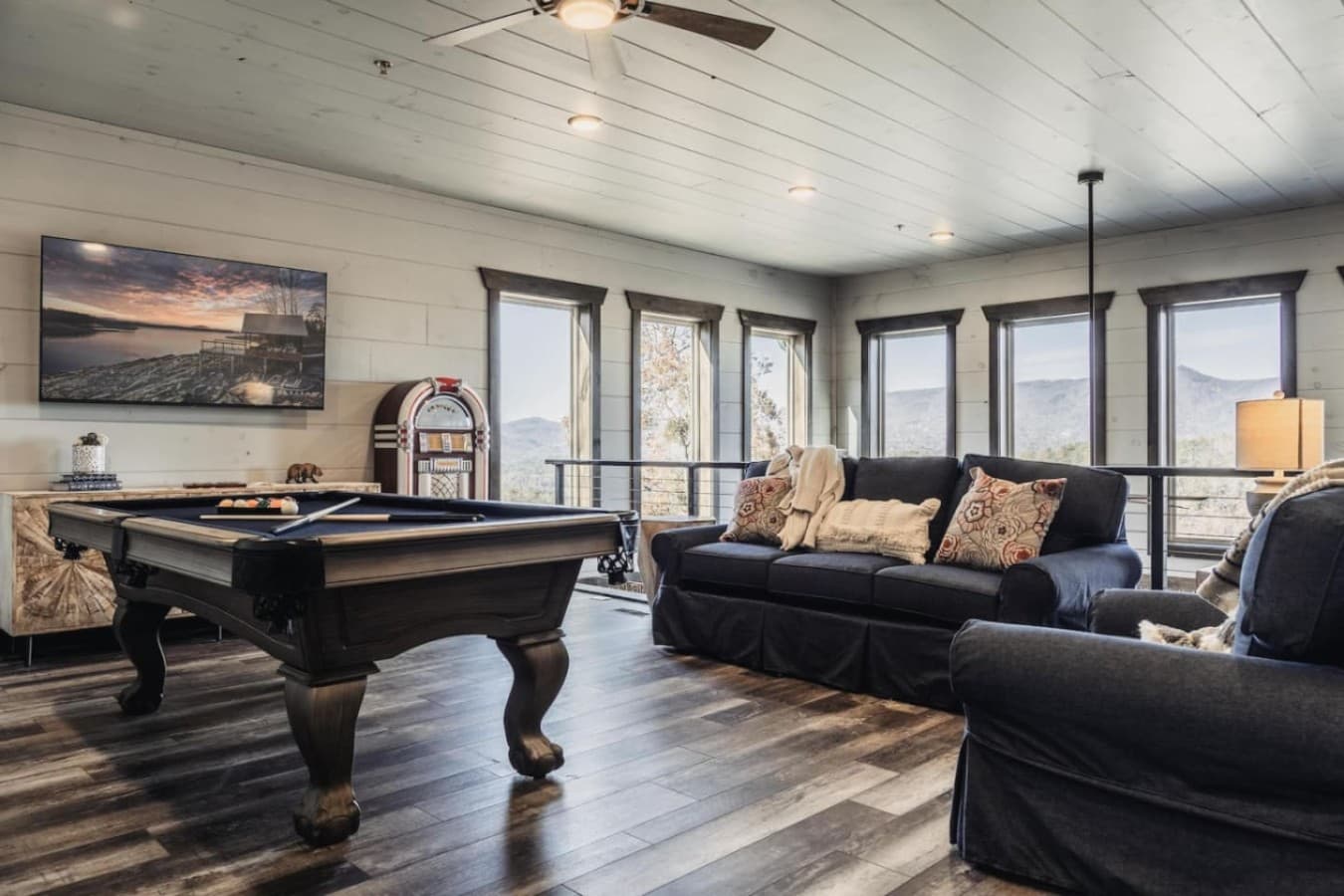 Spacious game room (upstairs) with a large TV, sofas, a pool table as well as a jukebox
