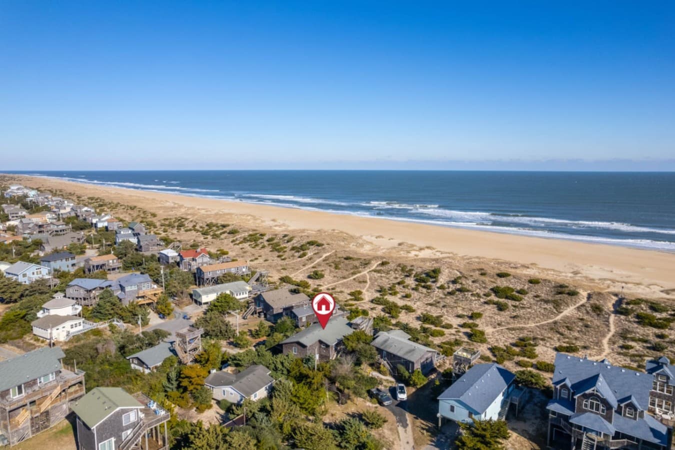 Sweeping coastal view over sandy shores, rooftops & endless ocean horizons.