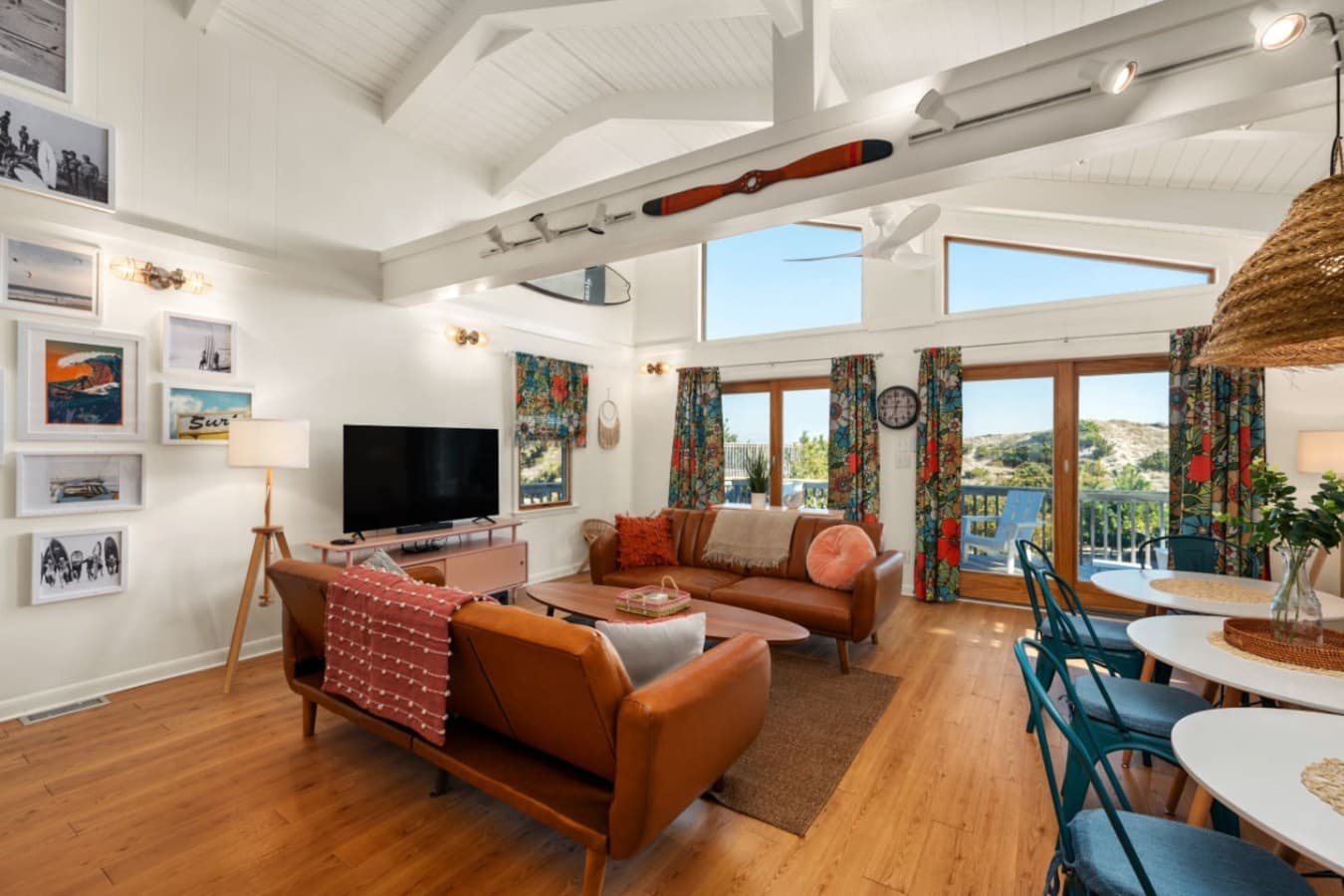 Bright, open living room w/ cozy seating, warm wood accents & sunlight pouring through large windows.