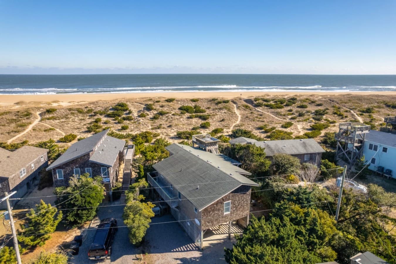Elevated aerial view showcasing the home nestled among greenery w/ the coastline stretching out beyond.