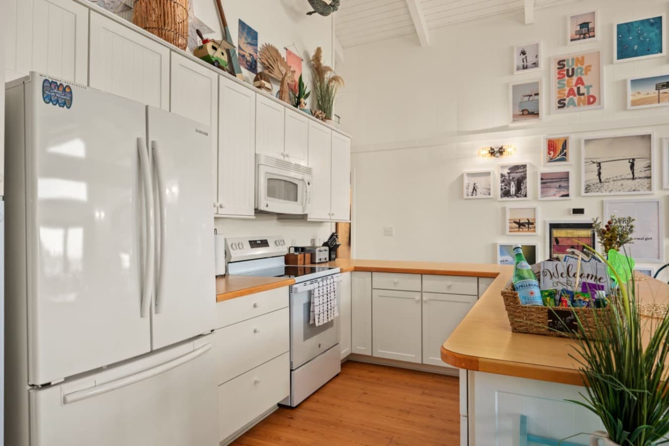 Functional kitchen setup w/ ample counter space, white cabinetry & beachy accents.