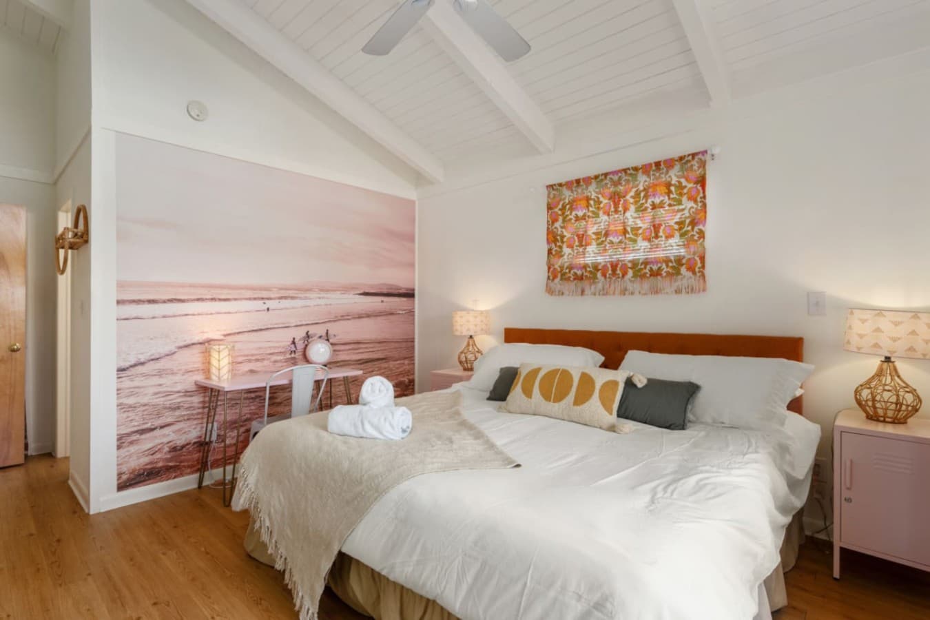 Peaceful bedroom w/ twin beds, soft linens & coastal art setting a calm tone.