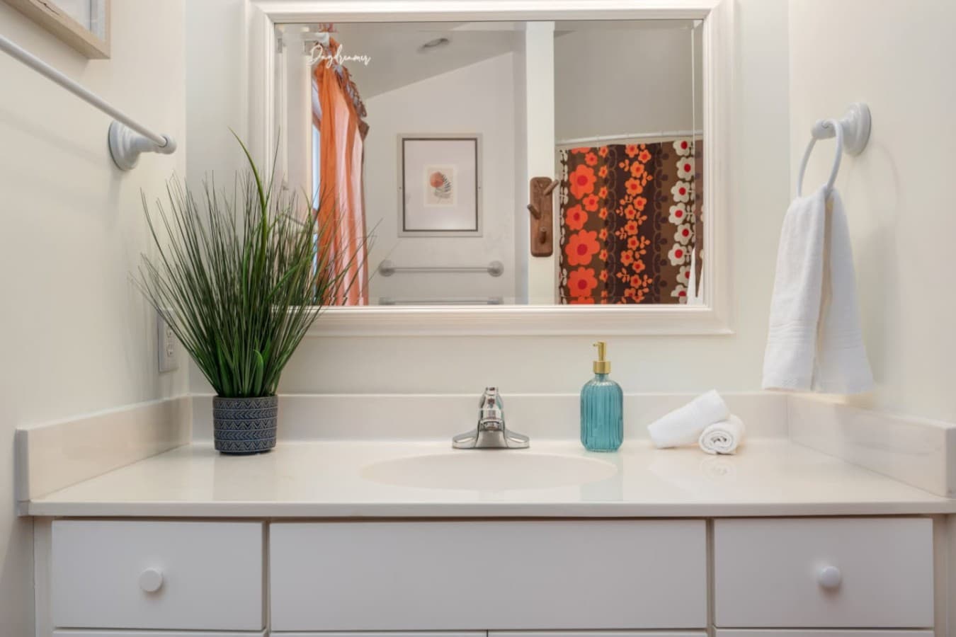 Bright bathroom vanity w/ a long counter, framed mirror & fresh towels set out.