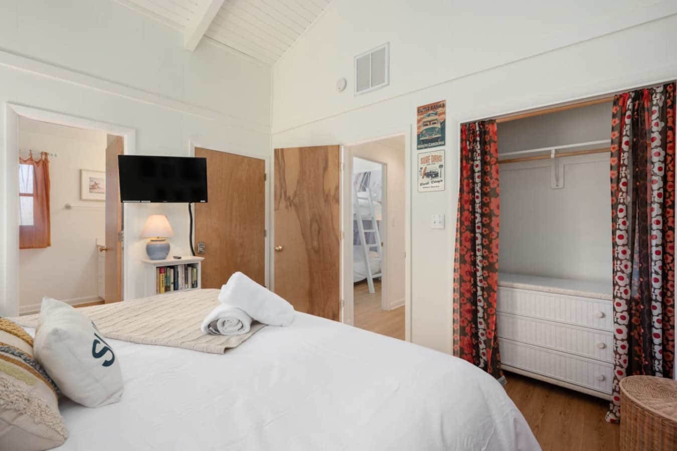 Bedroom w/ vaulted ceiling, wall-mounted TV & a curtained closet — restful and bright.