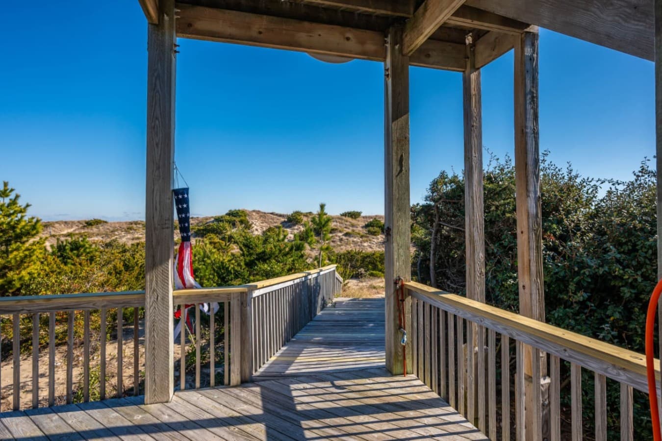 Covered deck w/ a wooden boardwalk running out toward the dune & beach.