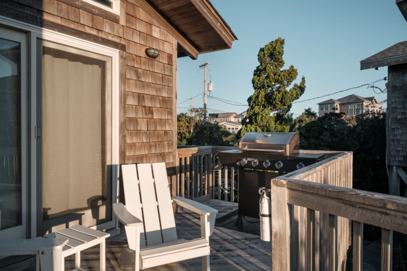 Deck w/ a gas grill & Adirondack chairs against the cedar-shake siding for easy cookouts.