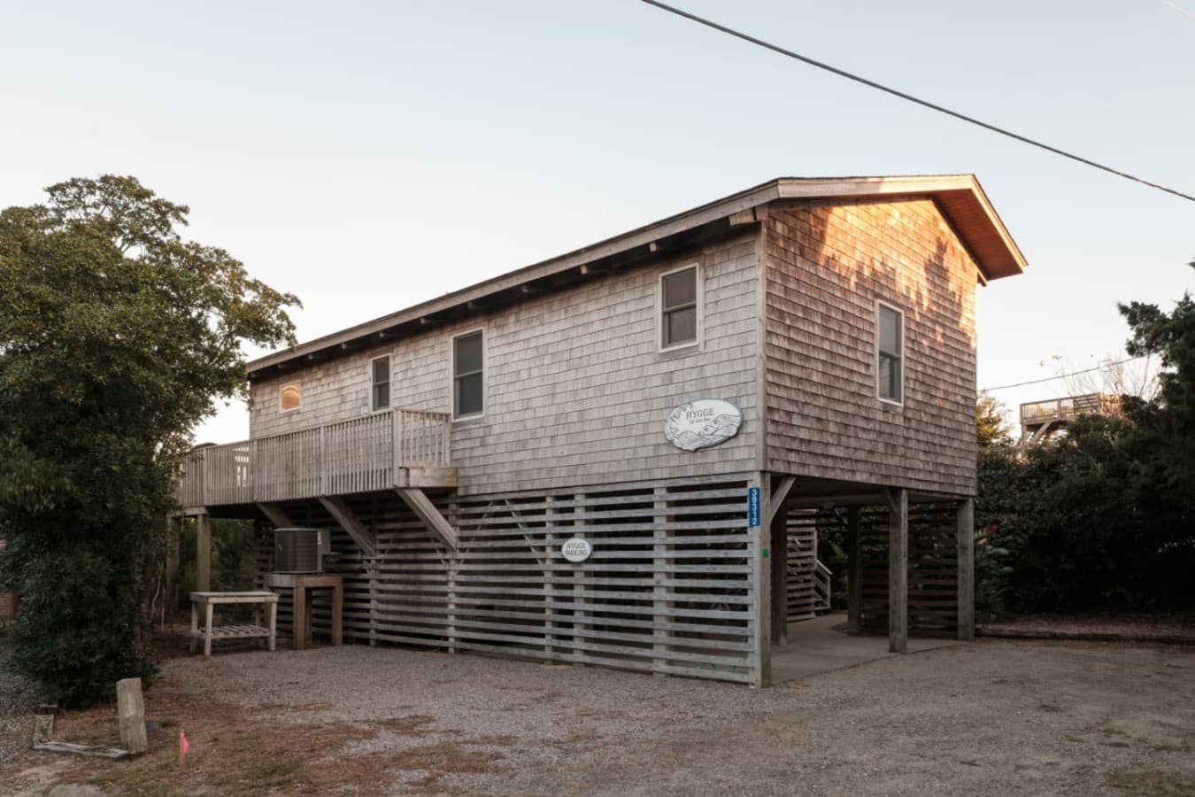Exterior of the cottage on pilings w/ a side deck & shaded parking underneath.