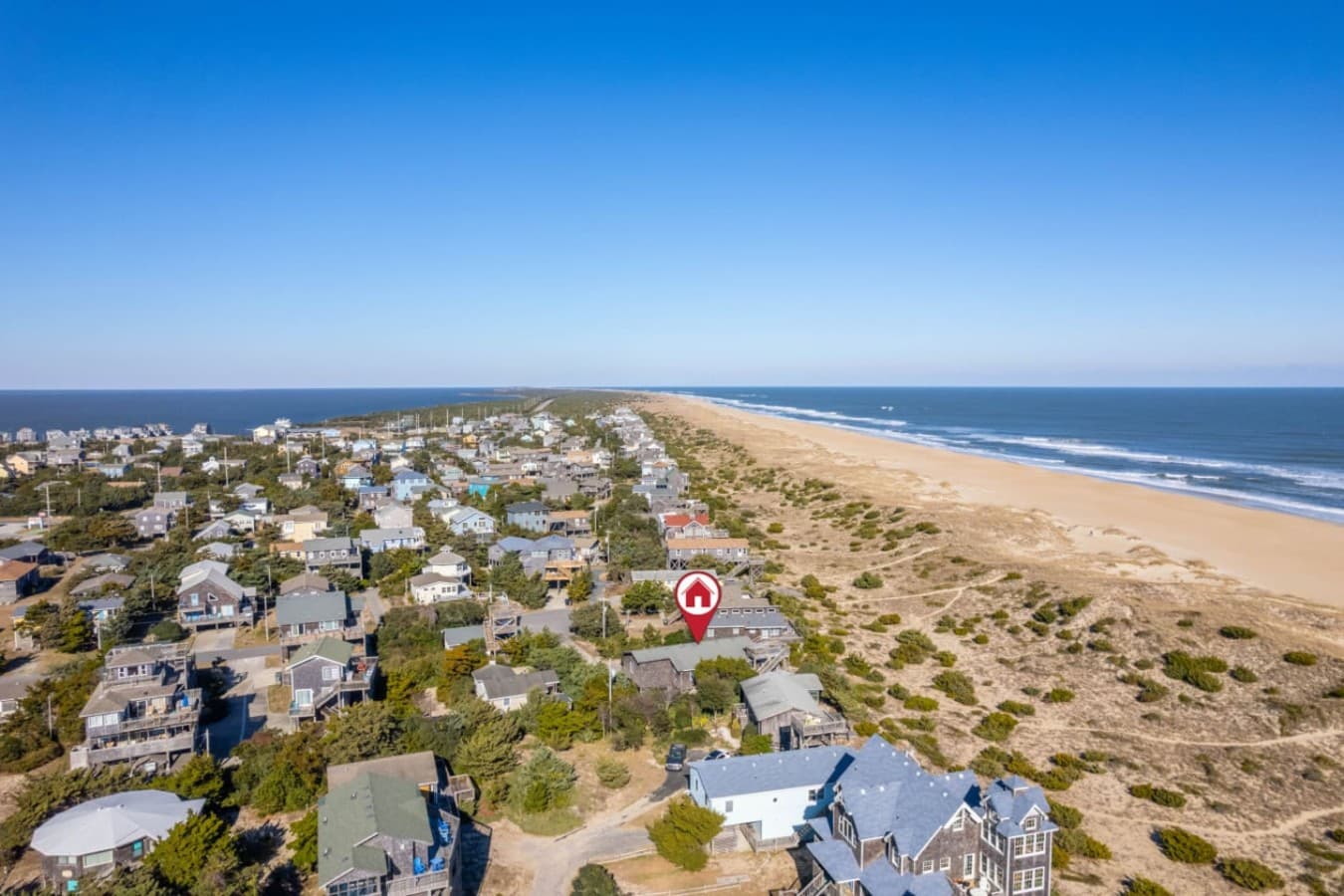 Aerial down the shoreline w/ the house set just behind the dune & beach.