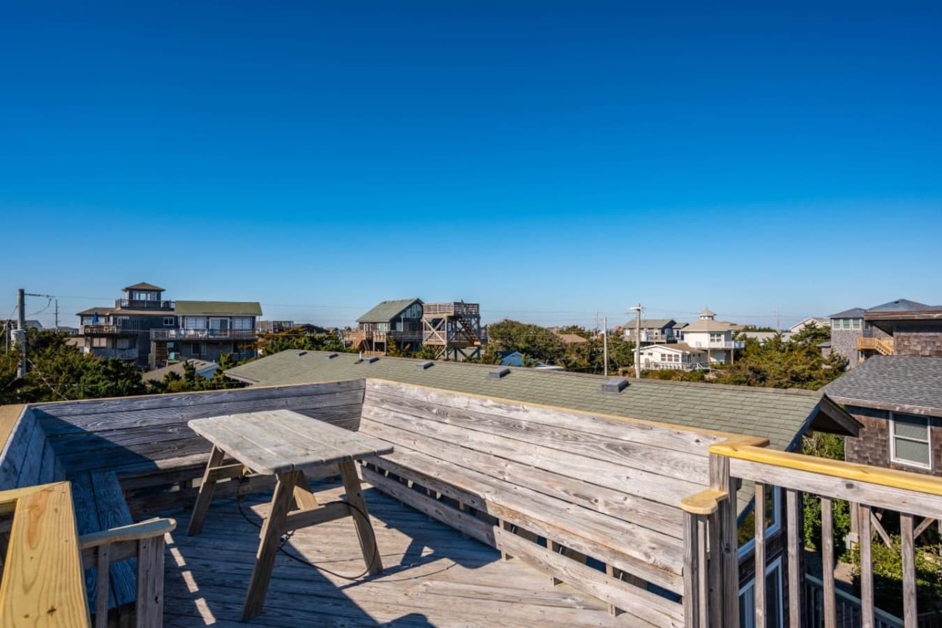 Rooftop-style view over nearby homes & greenery w/ the coastline in the distance.