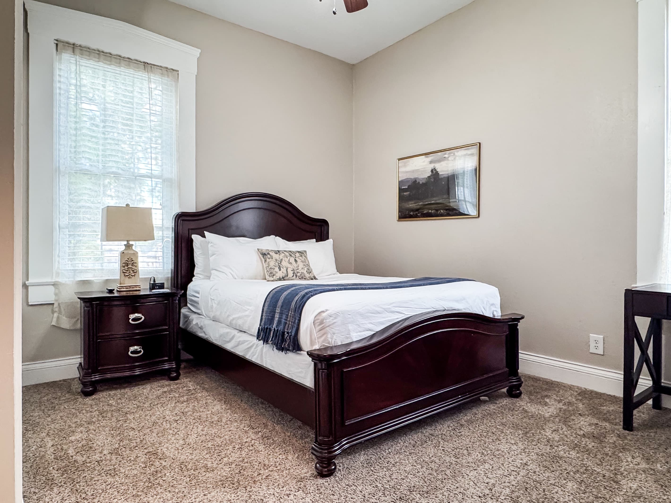 Spacious main level plush queen size bedroom with crisp white linens and full bathroom with combo tub and shower off the hallway at Mini Aussie Cottage.