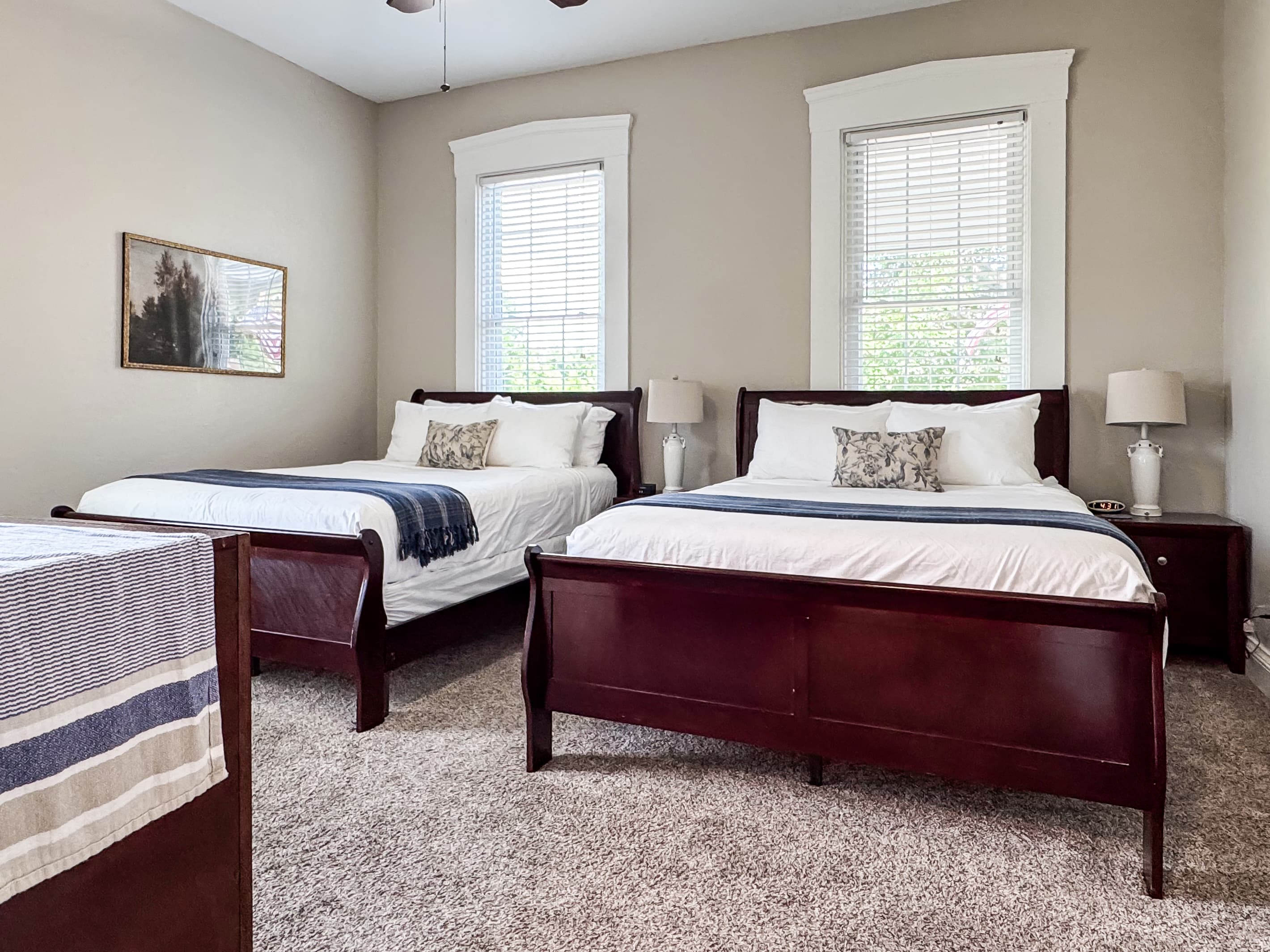 Spacious main level plush queen size bedroom with crisp white linens and full bathroom with combo tub and shower off the hallway at Mini Aussie Cottage.