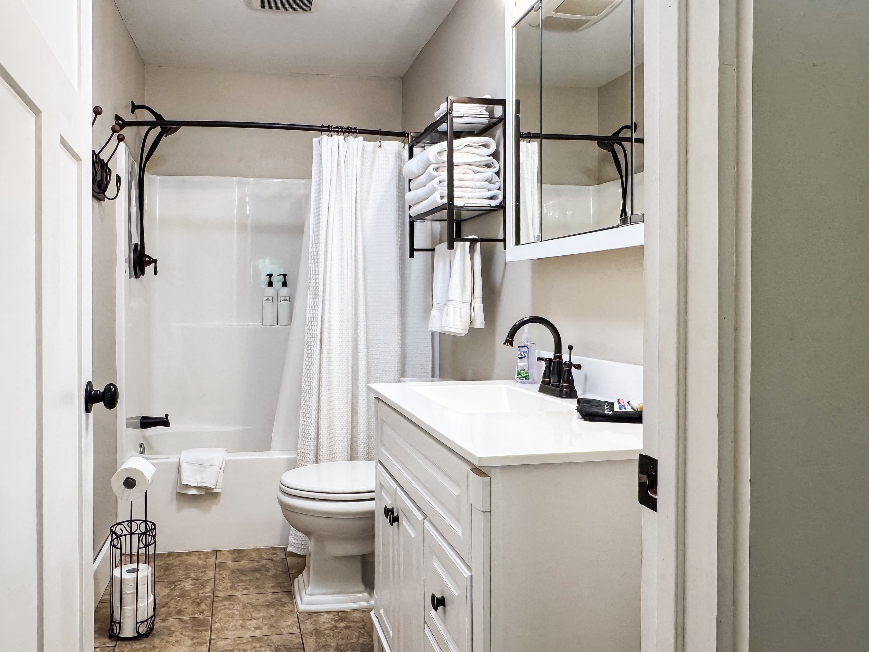 Modern main level full bathroom with combo tub and shower in the hallway at Mini Aussie Cottage.