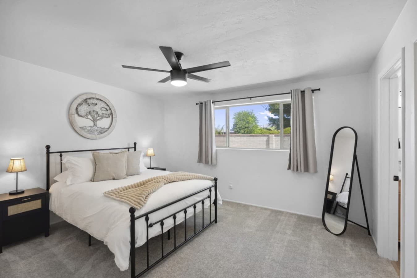 Bright bedroom w/ ceiling fan, plush bedding & a calm setup for restful nights.