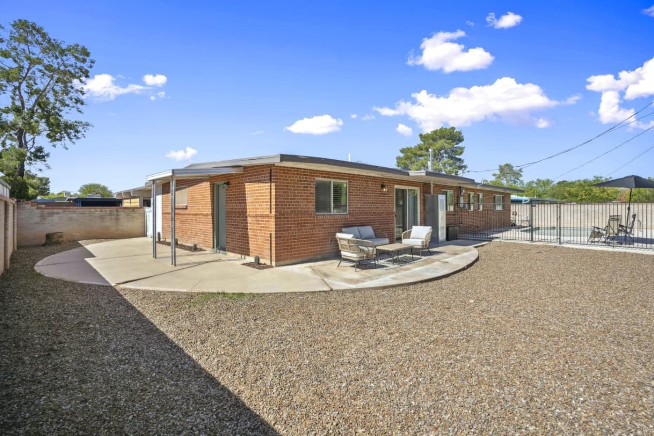 Spacious backyard w/ patio seating and clean lines, ideal for relaxing outdoors under open skies.