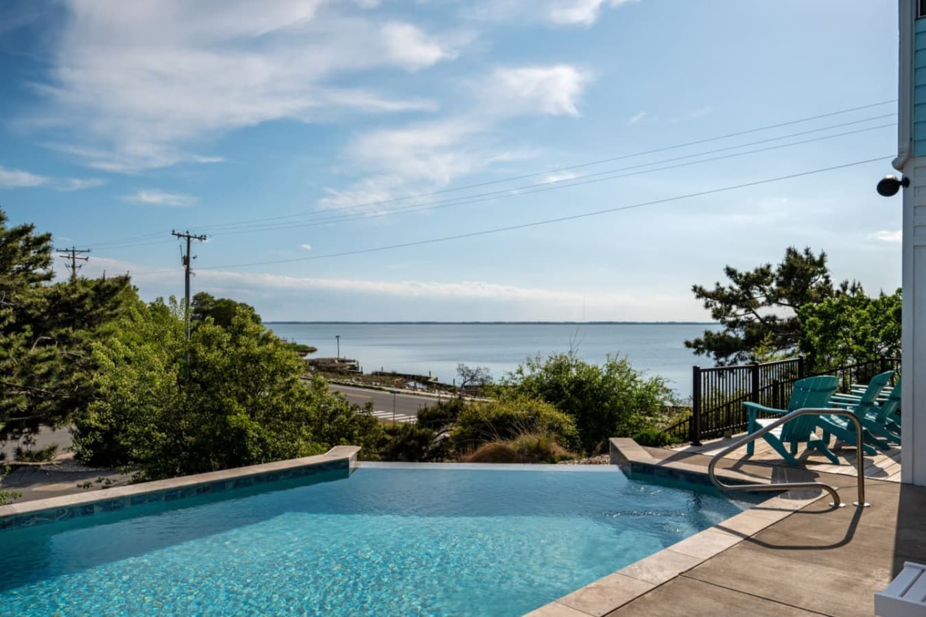 Pool deck w/ Adirondack chairs & the sound stretching out past the treeline.
