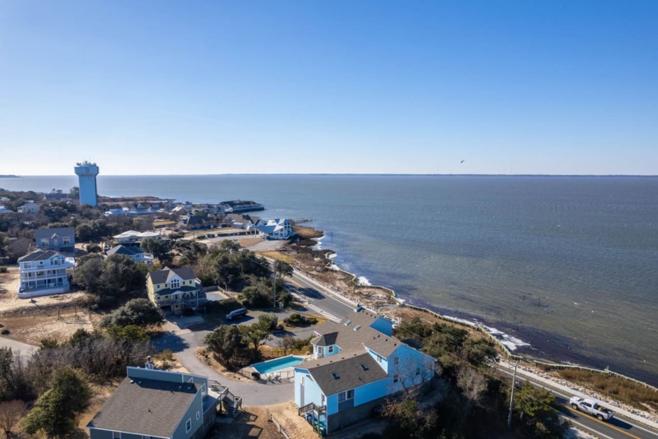 Wide coastal aerial capturing the shoreline, inlets, & expansive water views on the horizon.