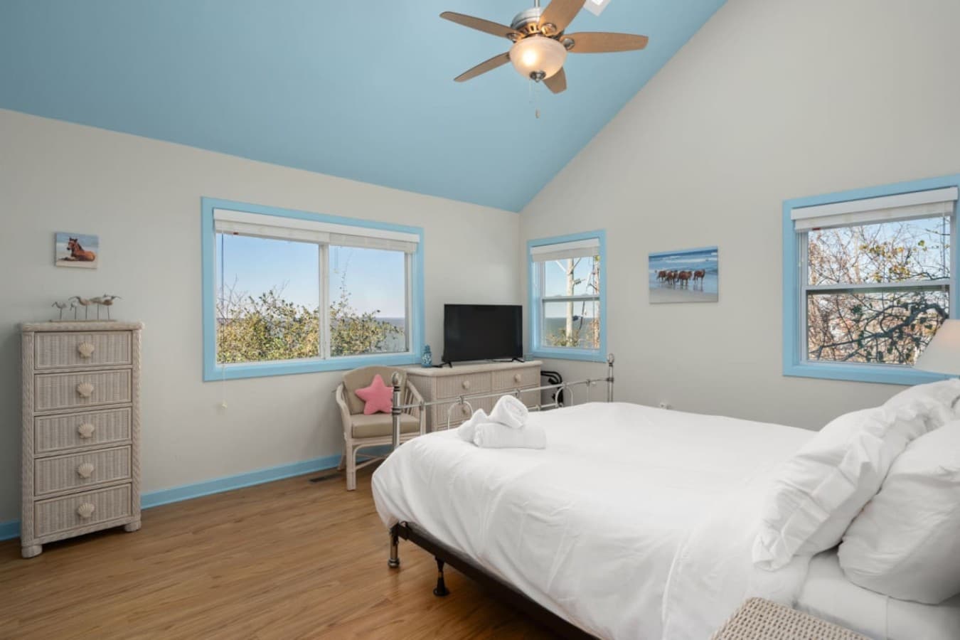 Inviting bedroom w/ calming tones, framed artwork, & a relaxed beach-house feel.