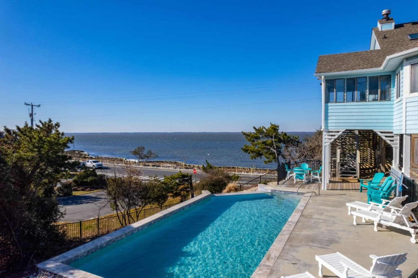 Exterior view w/ pool, decks & the sound as a backdrop, capturing the coastal setting.