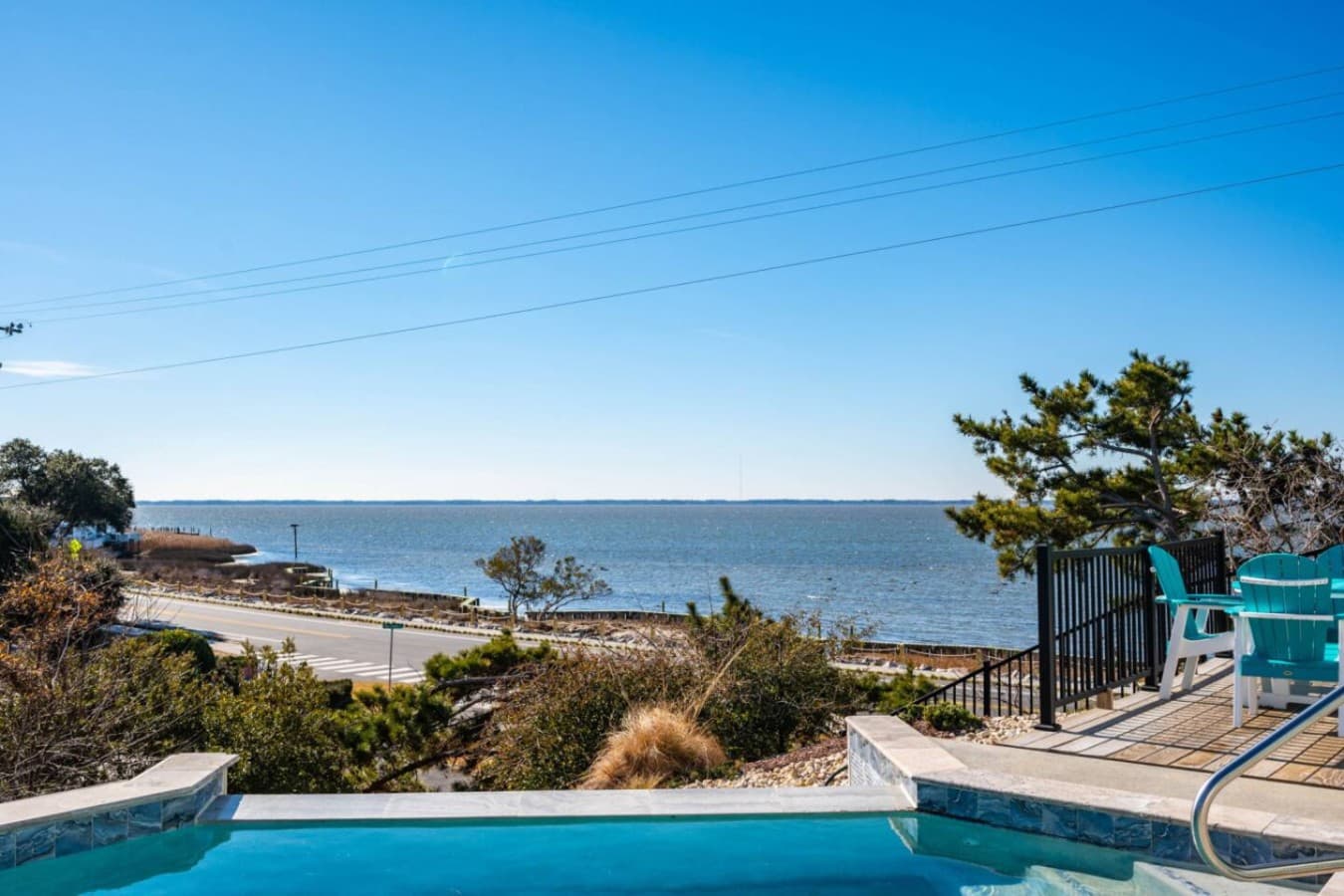 Pool's edge looking out over low scrub to the flat water of the sound.