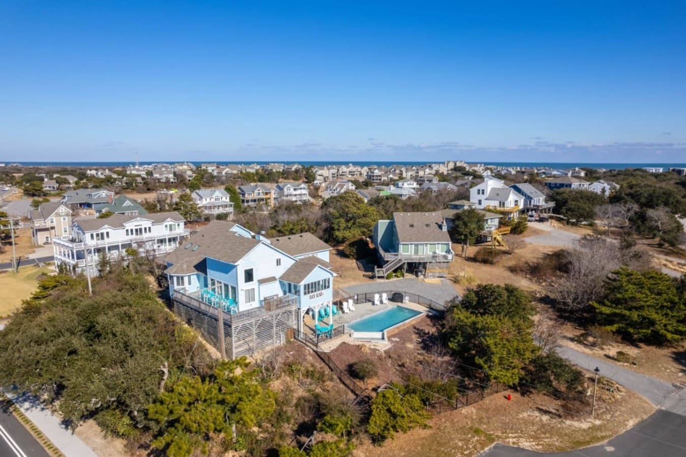 Aerial of the home & pool tucked into the maritime scrub w/ the sound on the horizon.