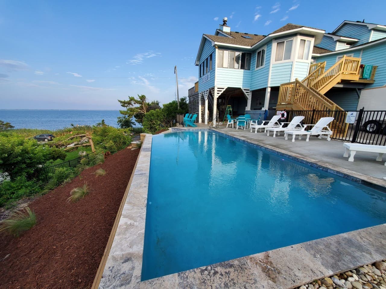 Pool & deck stack at the back of the house w/ loungers lined up along the far edge.
