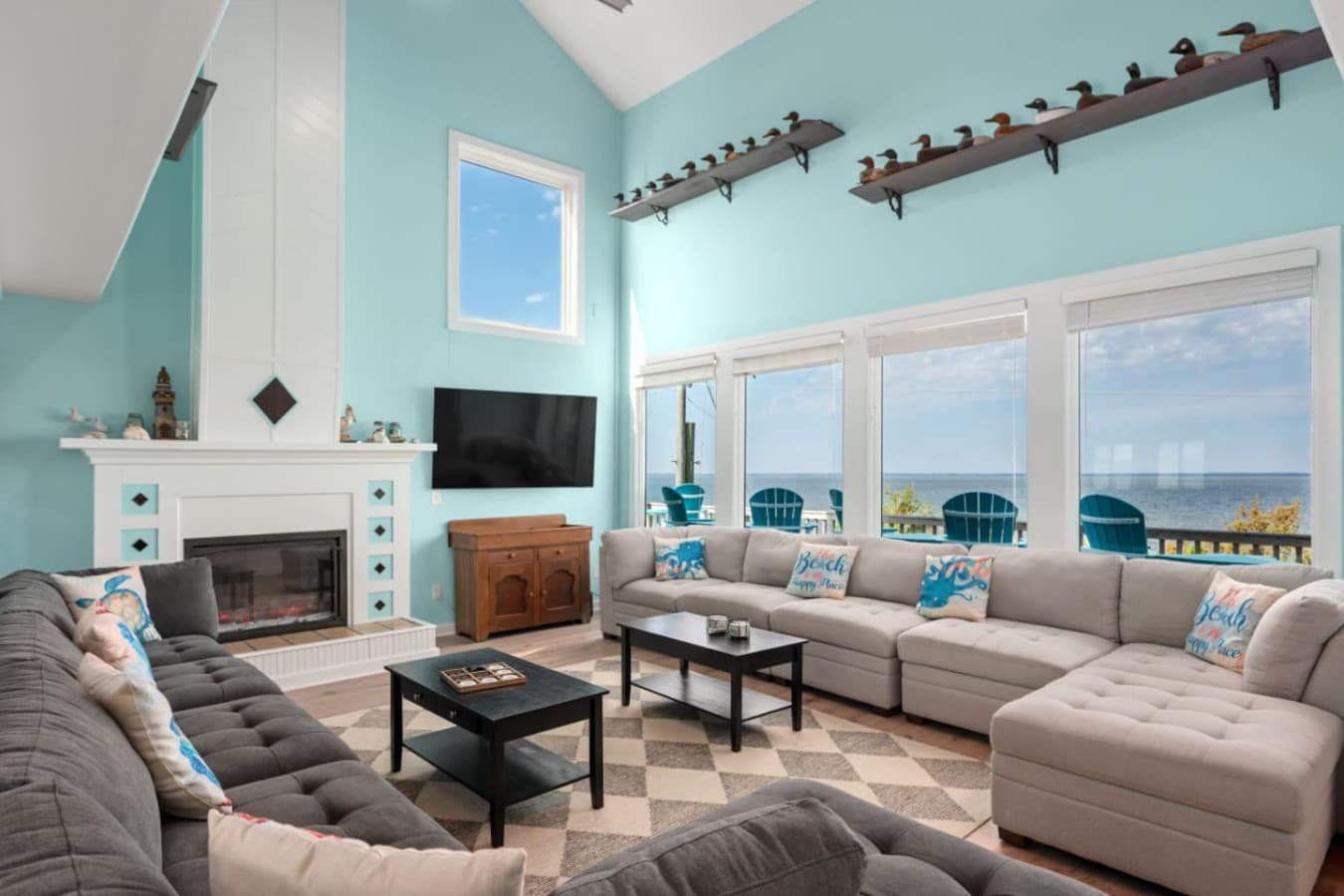 Great room w/ vaulted ceiling, wraparound sectional, fireplace & windows onto the sound-view deck.
