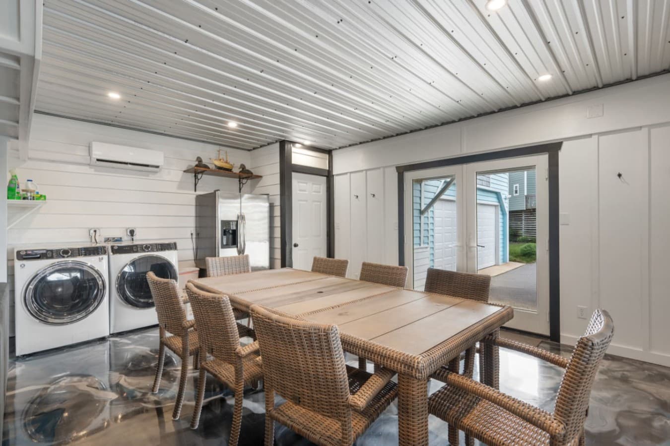 Garage rec room w/ a long table for group meals, washer & dryer & a door out to the drive.