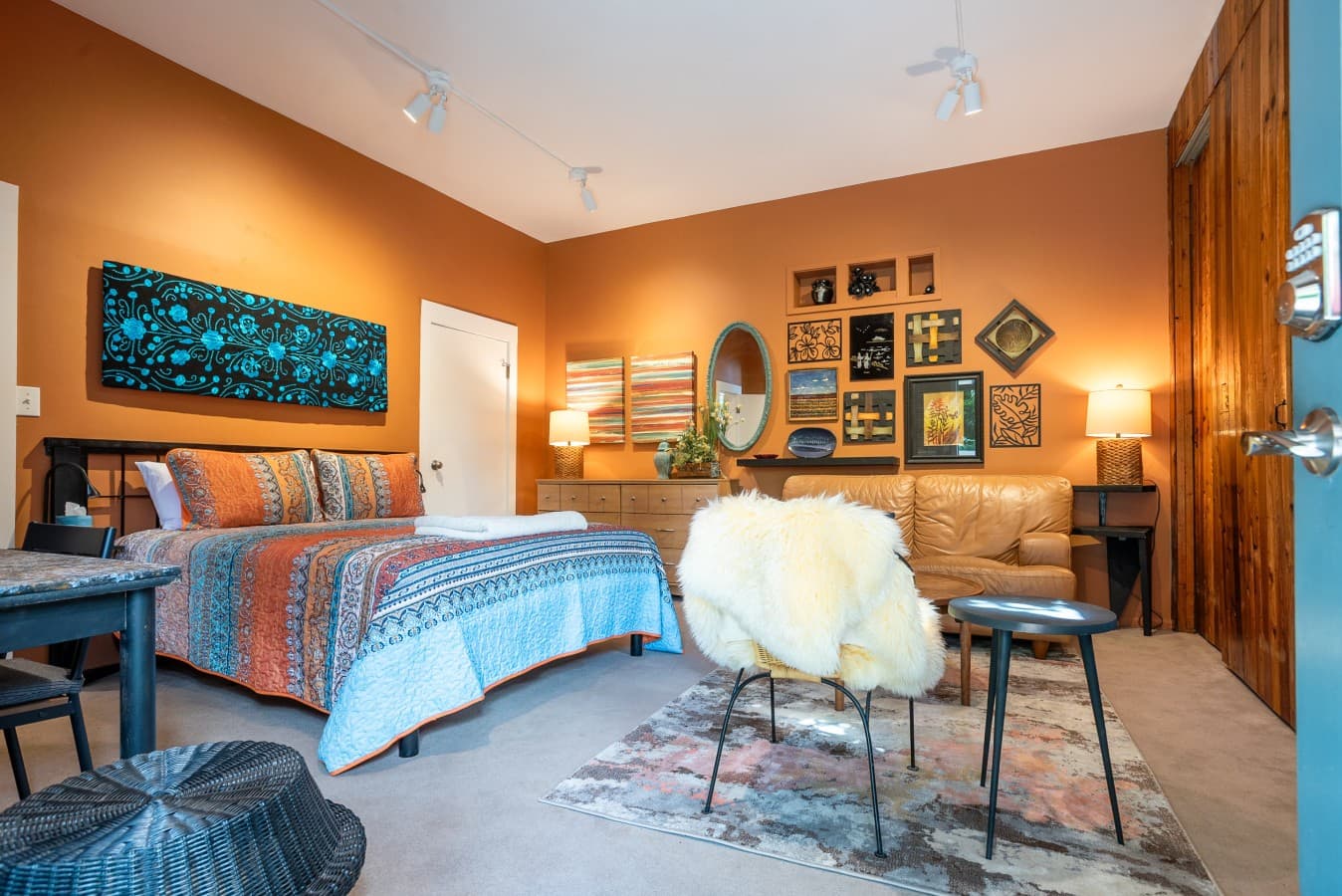 This warm, art-filled studio offers a relaxing space with boho décor and unique charm. It features a queen-size bed, a dedicated workspace, a cozy sofa, and a stylish accent chair..jpg