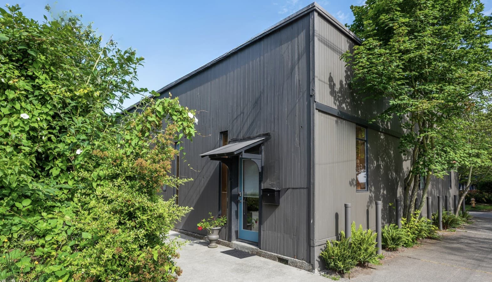 Modern gray facade with lush greenery, private entrance.png