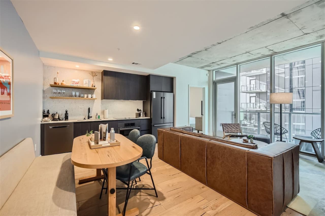 The dining room is seamlessly connected to a living room with floor-to-ceiling windows, offering a breathtaking city view and creating an elegant and captivating space for both dining and relaxation.